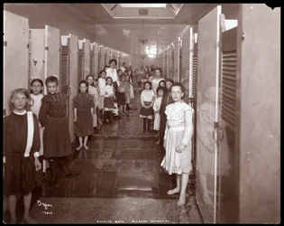Vista interior de mujeres jóvenes frente a cabinas de baño en los Baños del Pueblo, Milbank Memorial, Nueva York, 1904